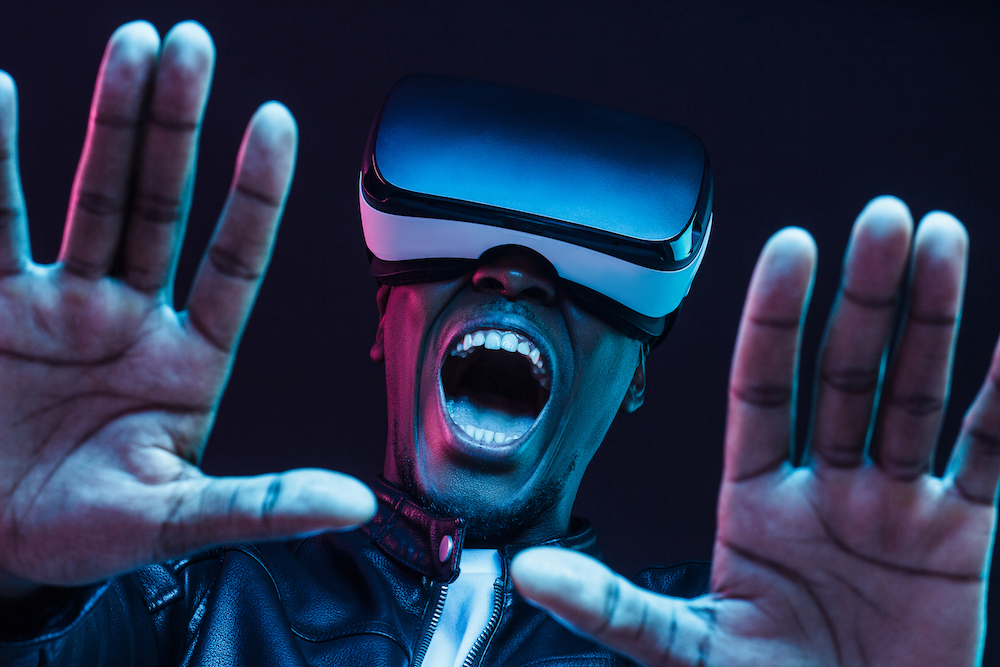 Excited young african man enjoying virtual reality with mouth wide open